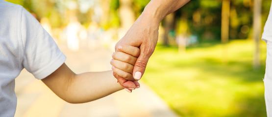 Close up of hands of a child and parent holding hands