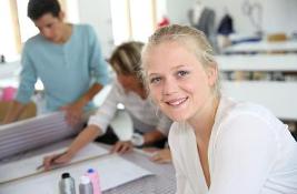 Woman sat in front of a desk, with people in the background