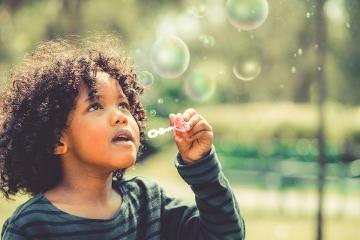 Happy child blowing bubbles in school garden