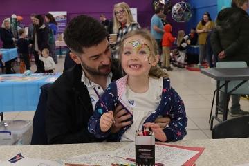 A dad with daughter colouring in a book